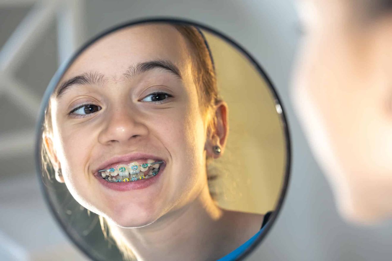 caucasian preteen girl with braces her teeth looking mirror 2 b3970a0e